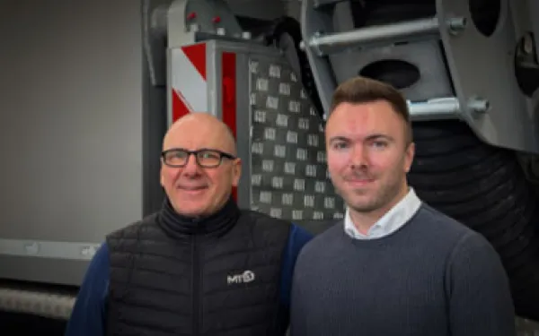 Zwei Mitarbeiter lächeln in die Kamera